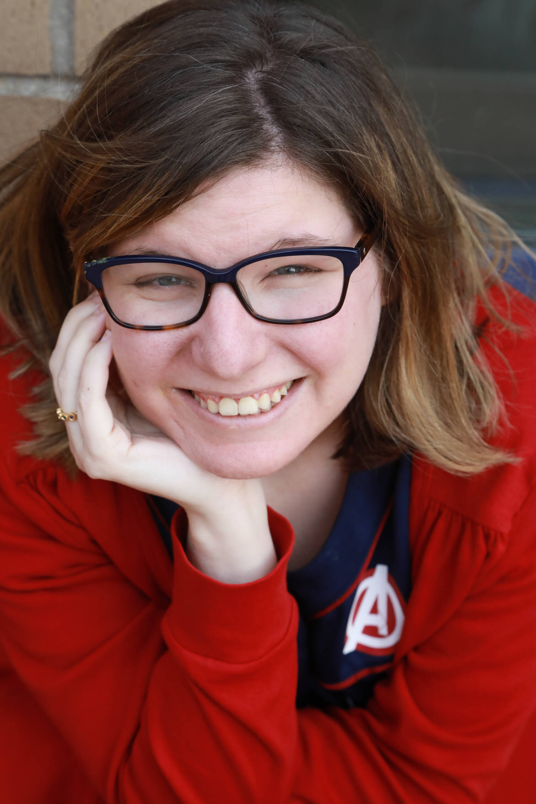 AX2A1416 Woman with brown hair and glasses, wearing a red sweater and smiling into the camera.