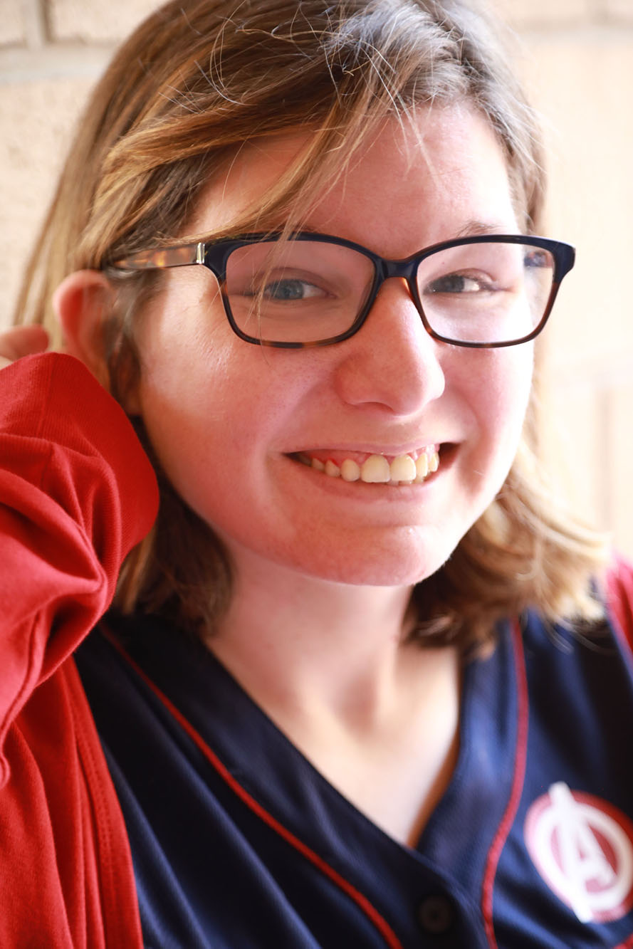 Light-skinned young woman wearing black glasses smiles at the camera.
