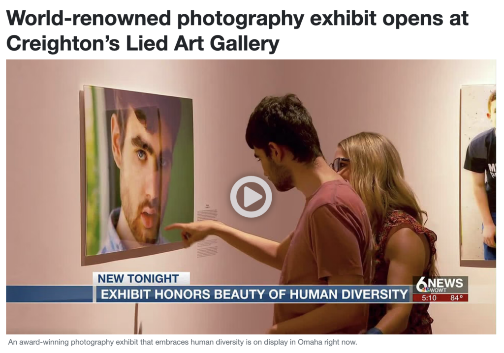ID: screenshot from a news video of a young man looking and pointing at a portrait of himself: a close-up photograph of a young, light-skinned boy with dark hair and green eyes hanging on a gallery wall.
