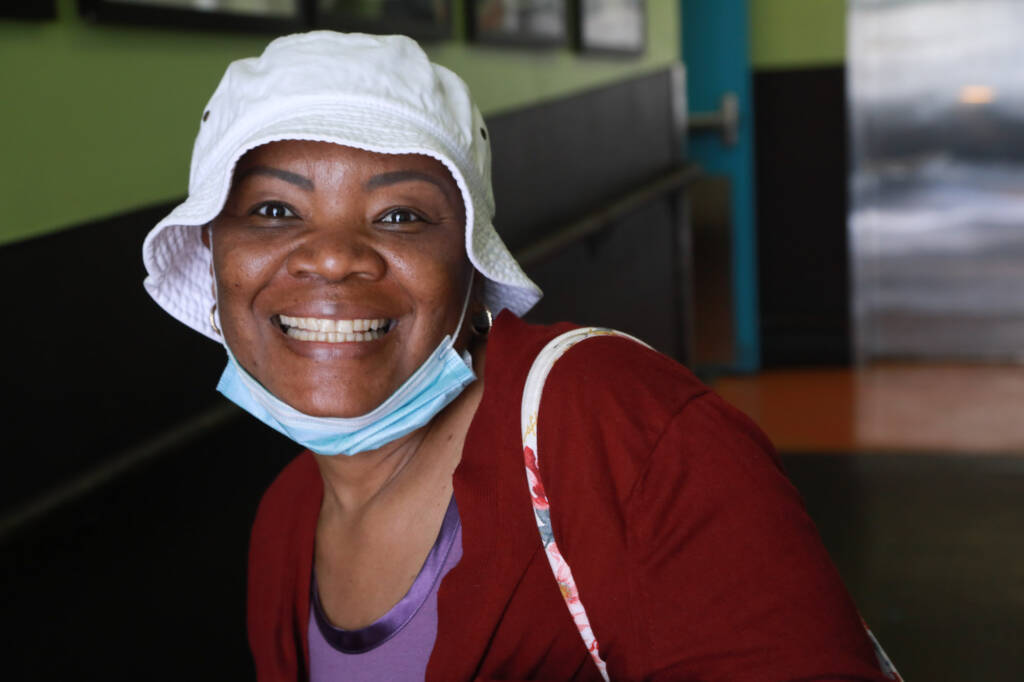 Woman wearing white hat and red sweater smiling.