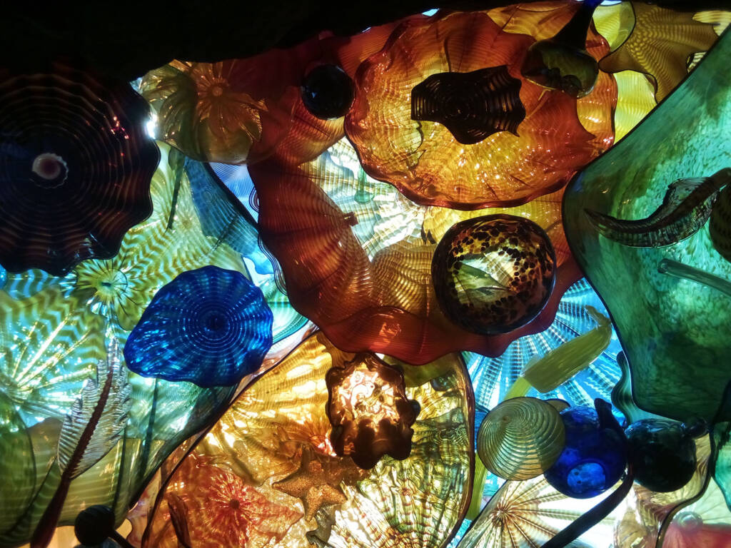 Brightly colored glass shapes in orange, blue, green, gold shot from below and lit from above.