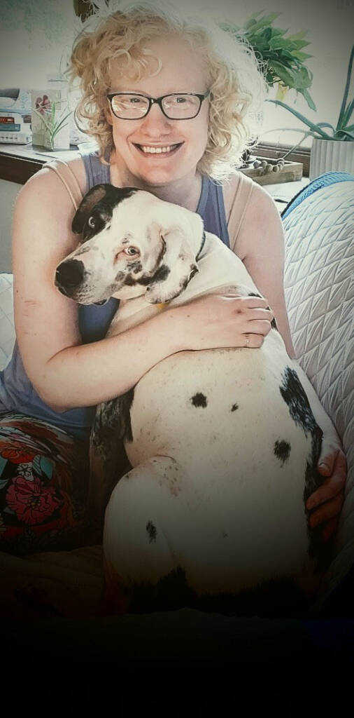 Woman holding a black and white dog. Both looking into the camera