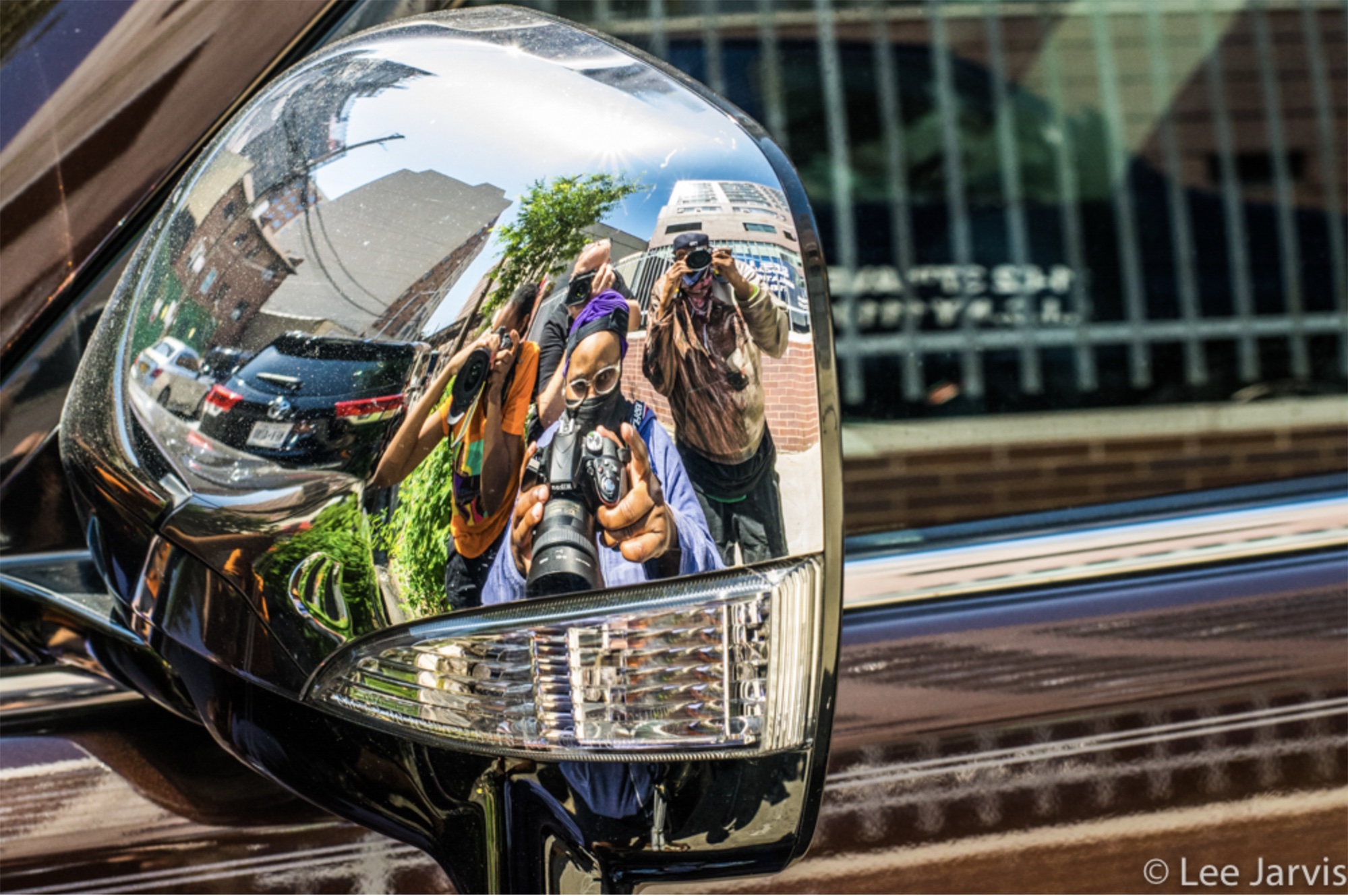 Reflection of 4 photographers in rear view mirror chrome.