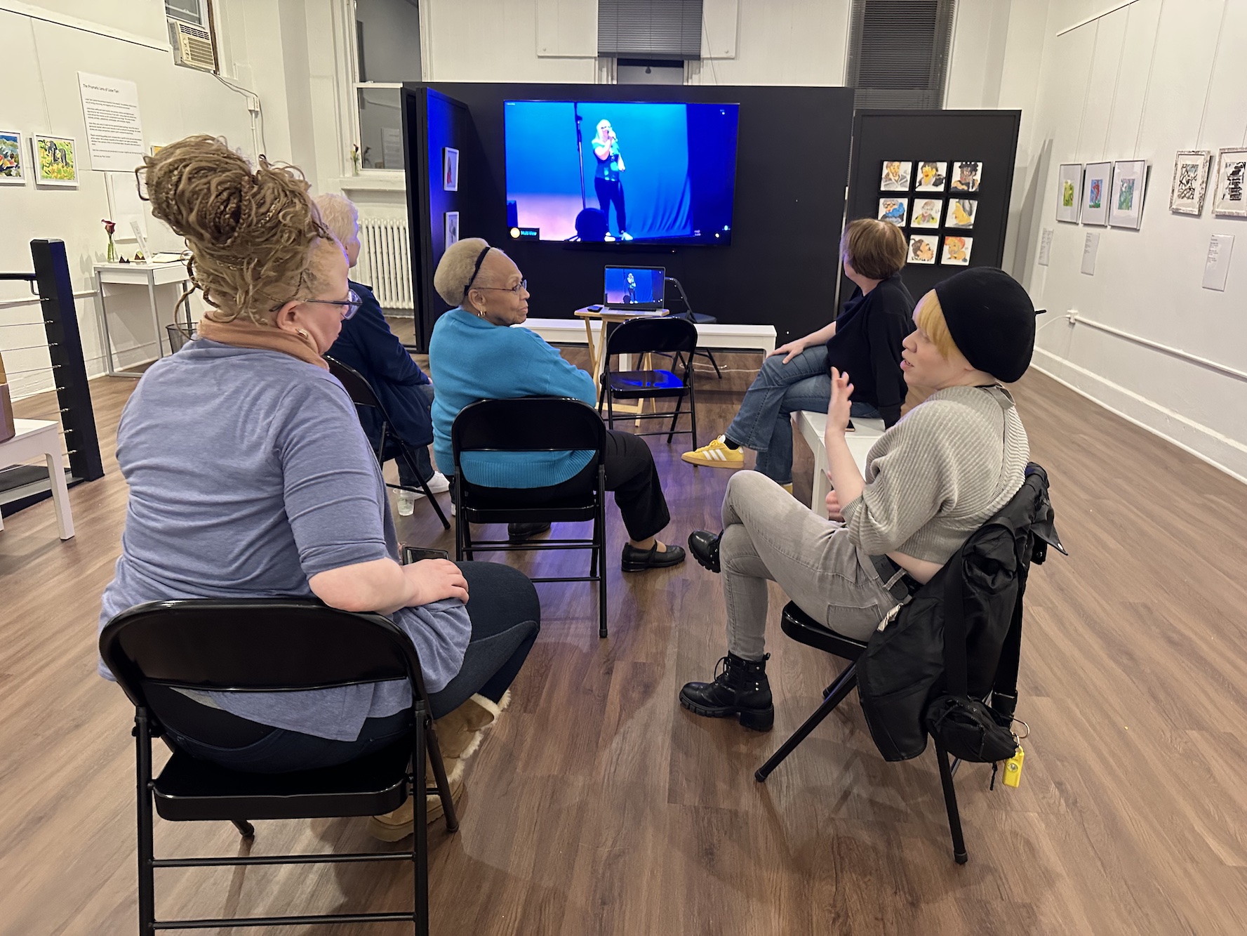 Group of friends with albinism watch a monitor in gallery.