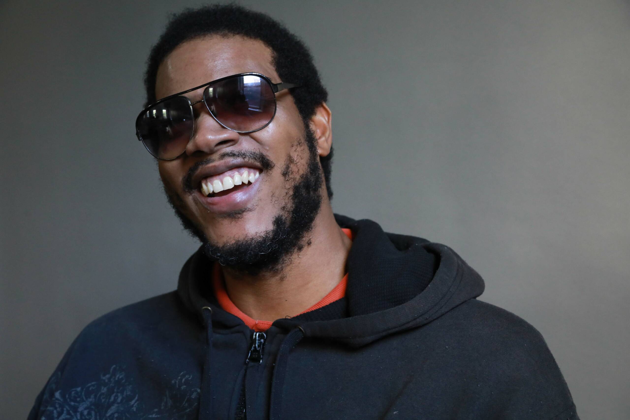 Man with dark brown skin, sunglasses and amazing smile.