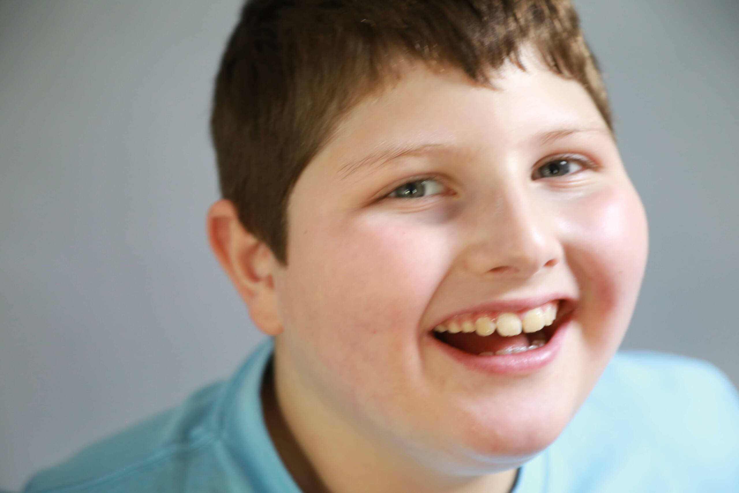 Boy with short brown hair and bright smile looking into the camera.