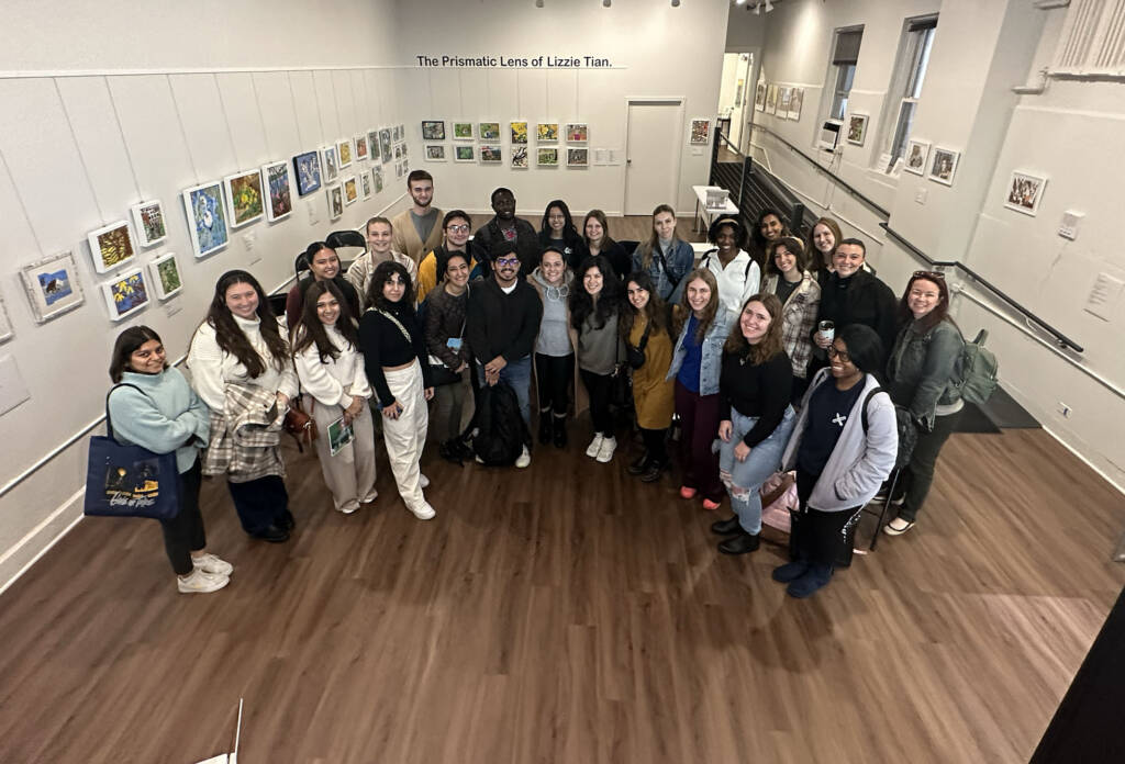 Group of 30 + people in gallery looking up to camera.