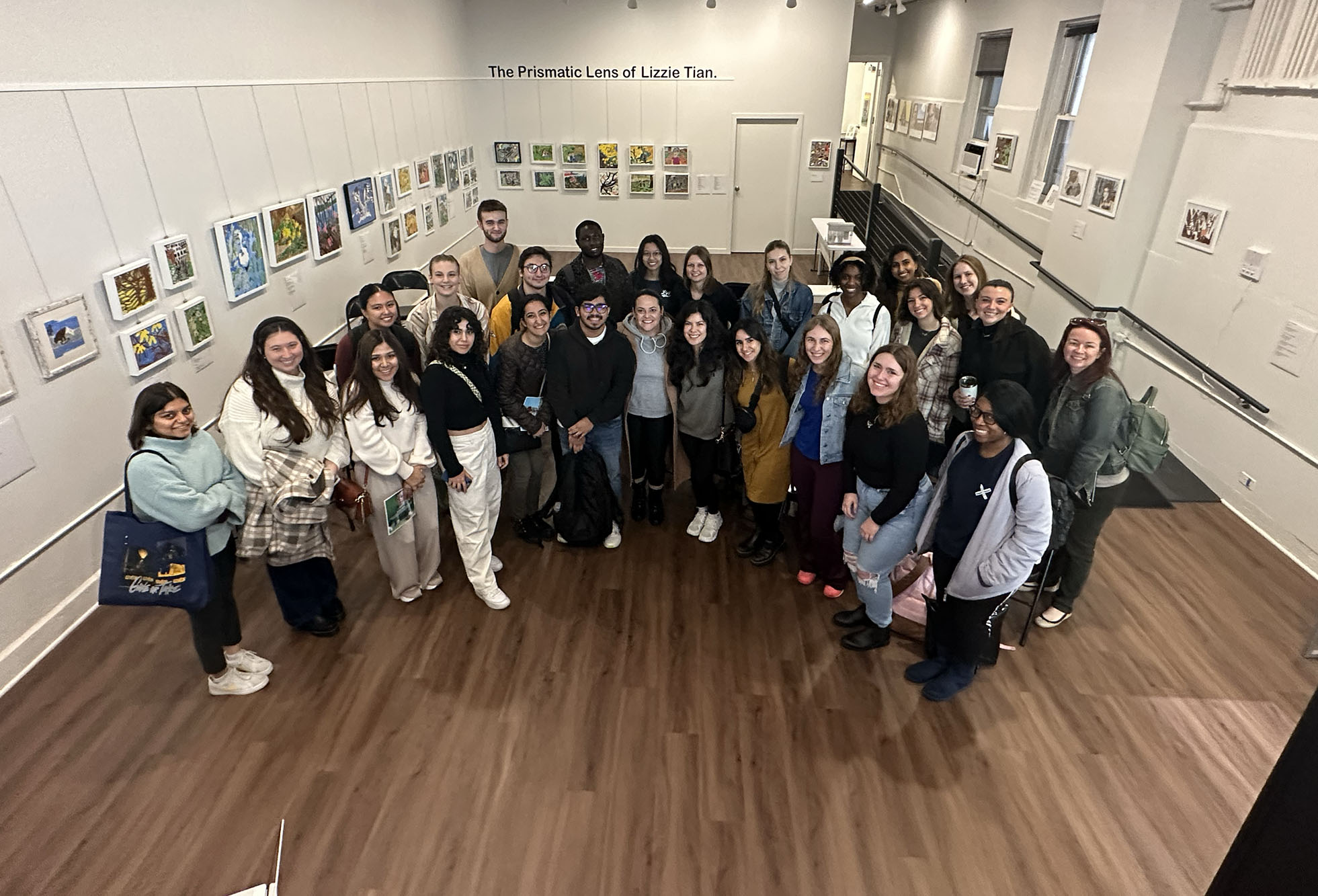 Group of 30 + people in gallery looking up to camera.
