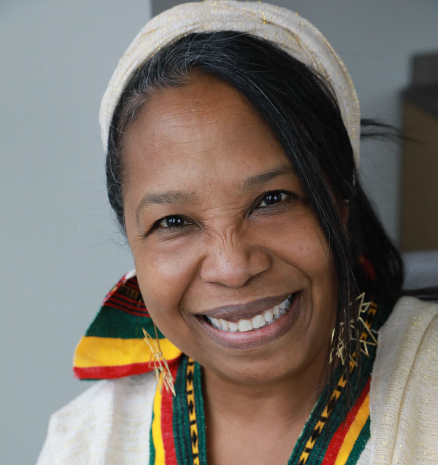 Woman wearing a tan and multi colored tunic with matching head band. i