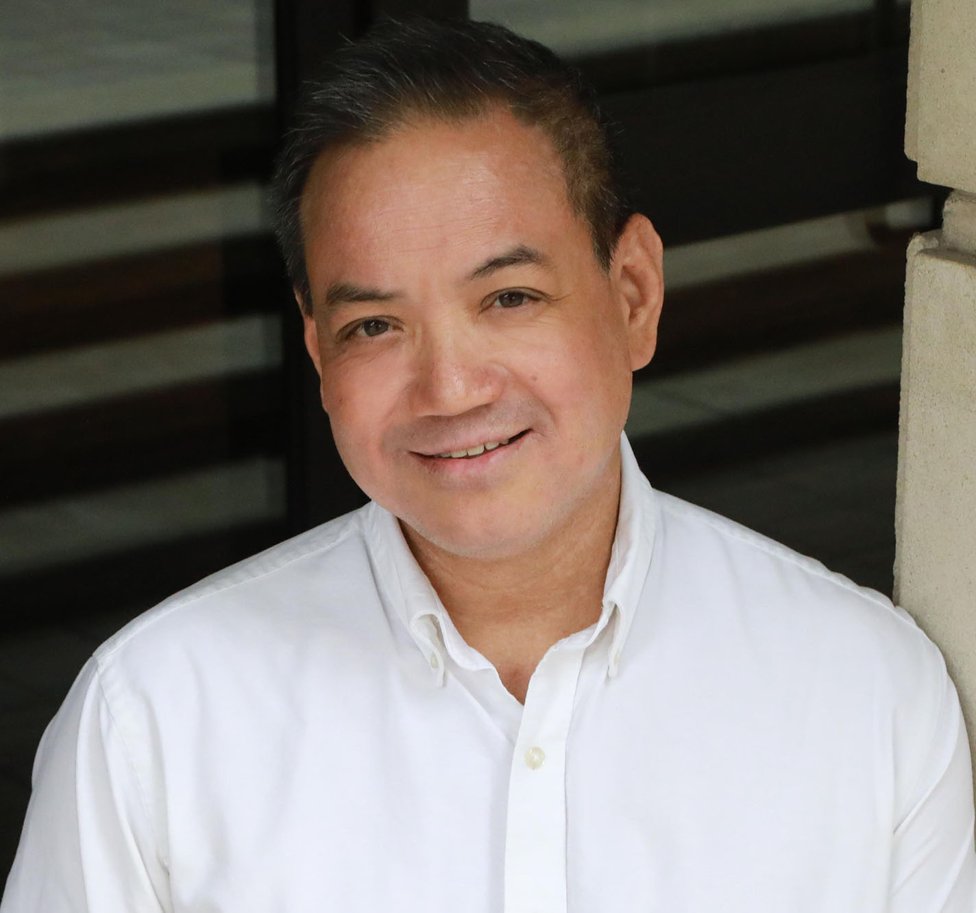 Man with dark hair and white shirt looking into the camera.