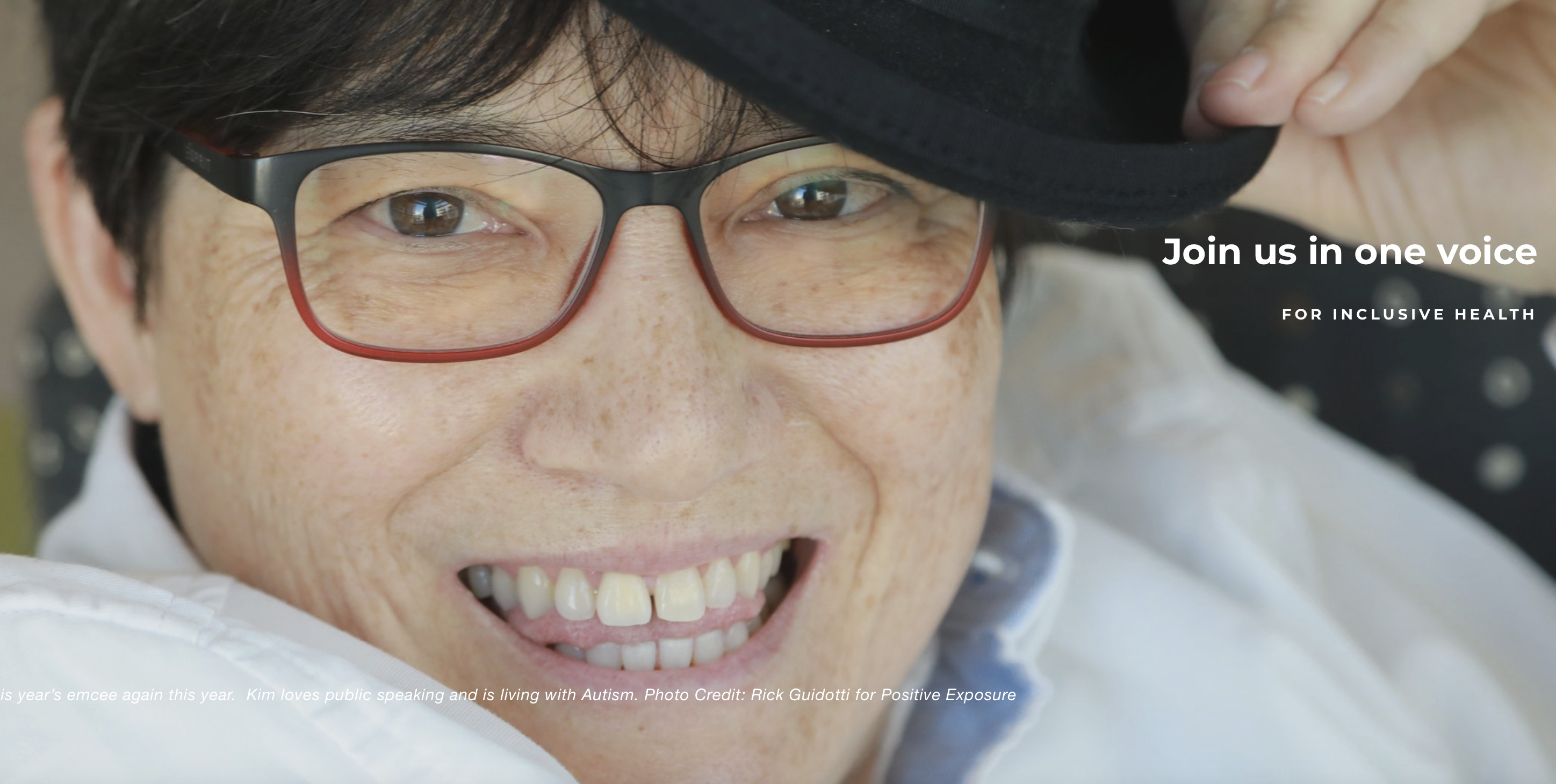 Woman with hat and glasses smiling into the camera.