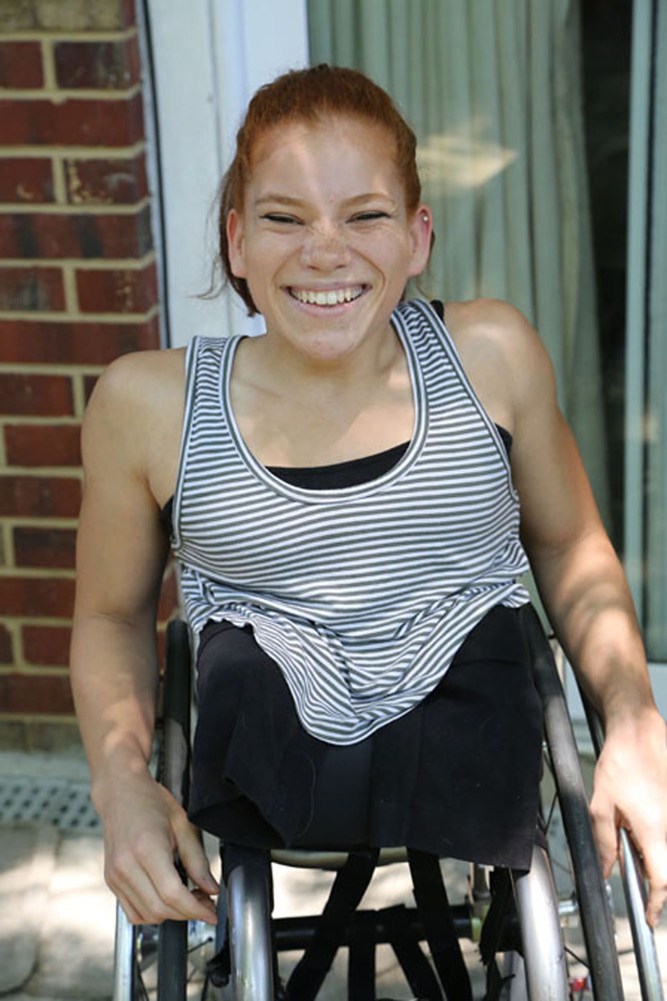 Woman with Sacral agenesis caudal regression sitting in wheelchair smiling at camera