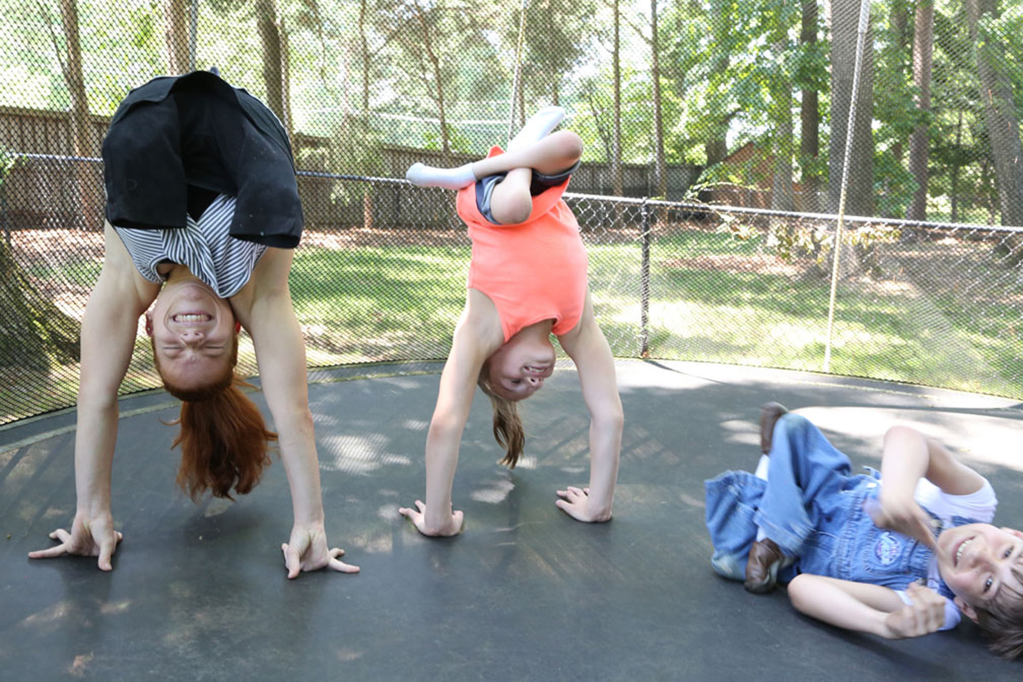 Three people with sacral agenesis caudal regression do handstands together on trampoline
