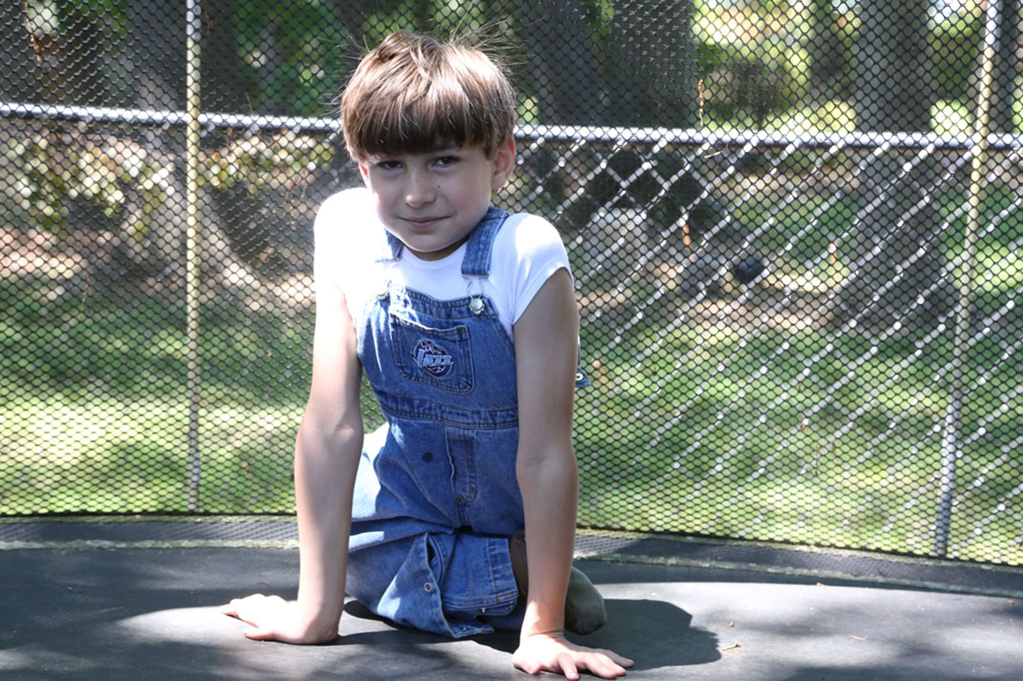 Young boy with sacral agenesis caudal regression on trampoline, looking at camera