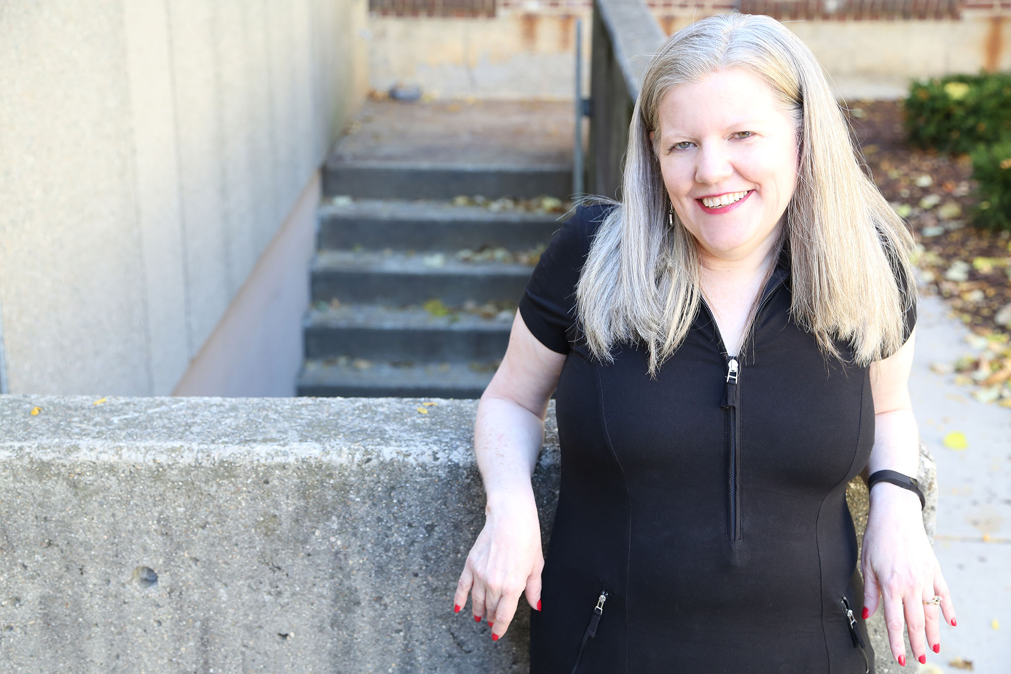 Lady with Hermansky-Pudlak syndrome leaning against a wall, smilling
