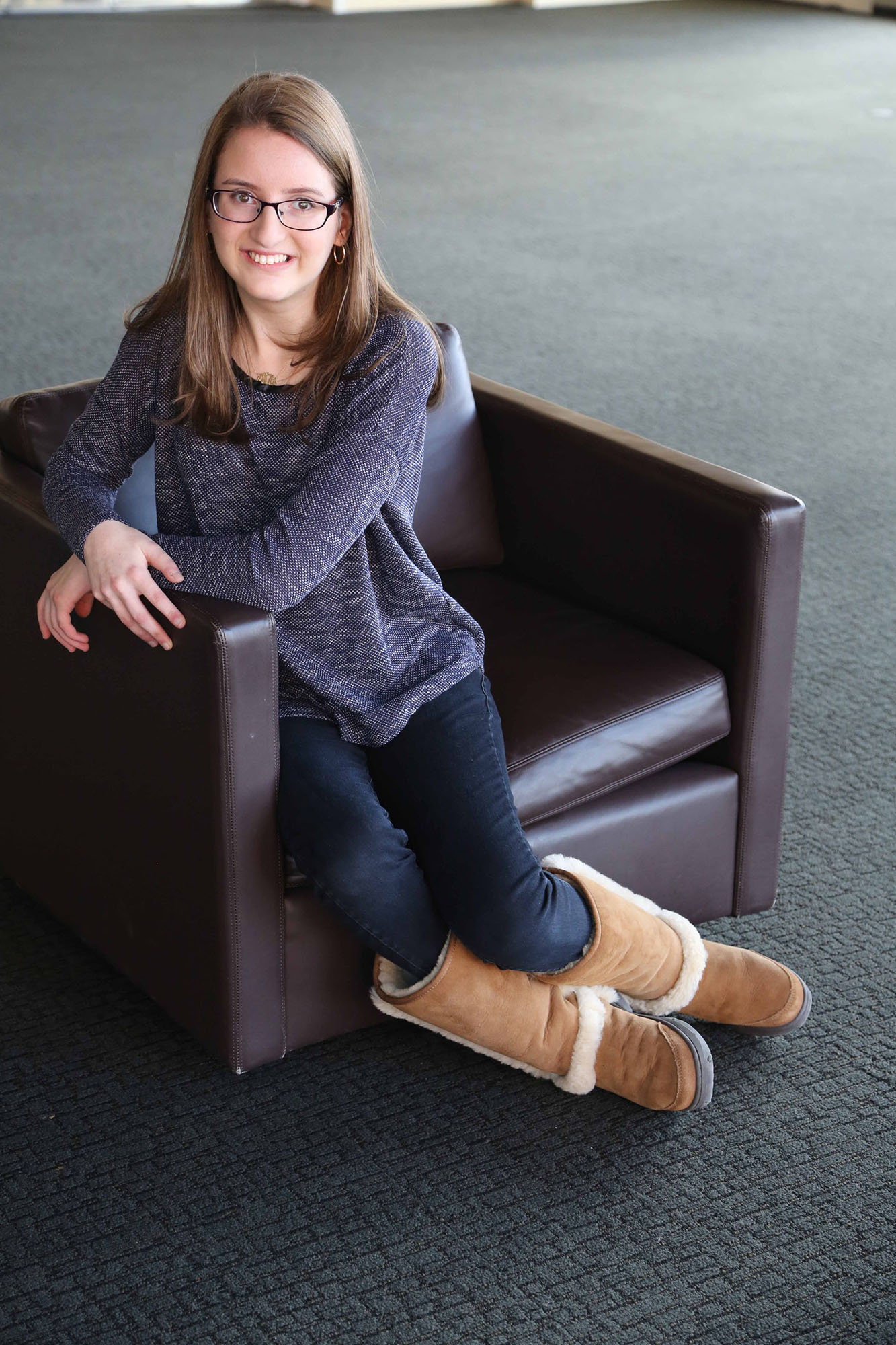Woman with Familial Dysautonomia sitting on a chair and smiling at the camera