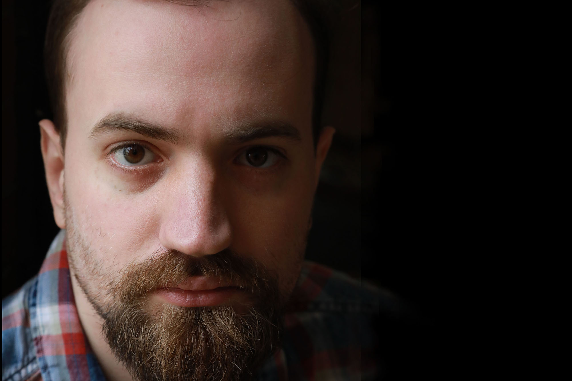 man with Autism wearing plaid shirt looks at camera.