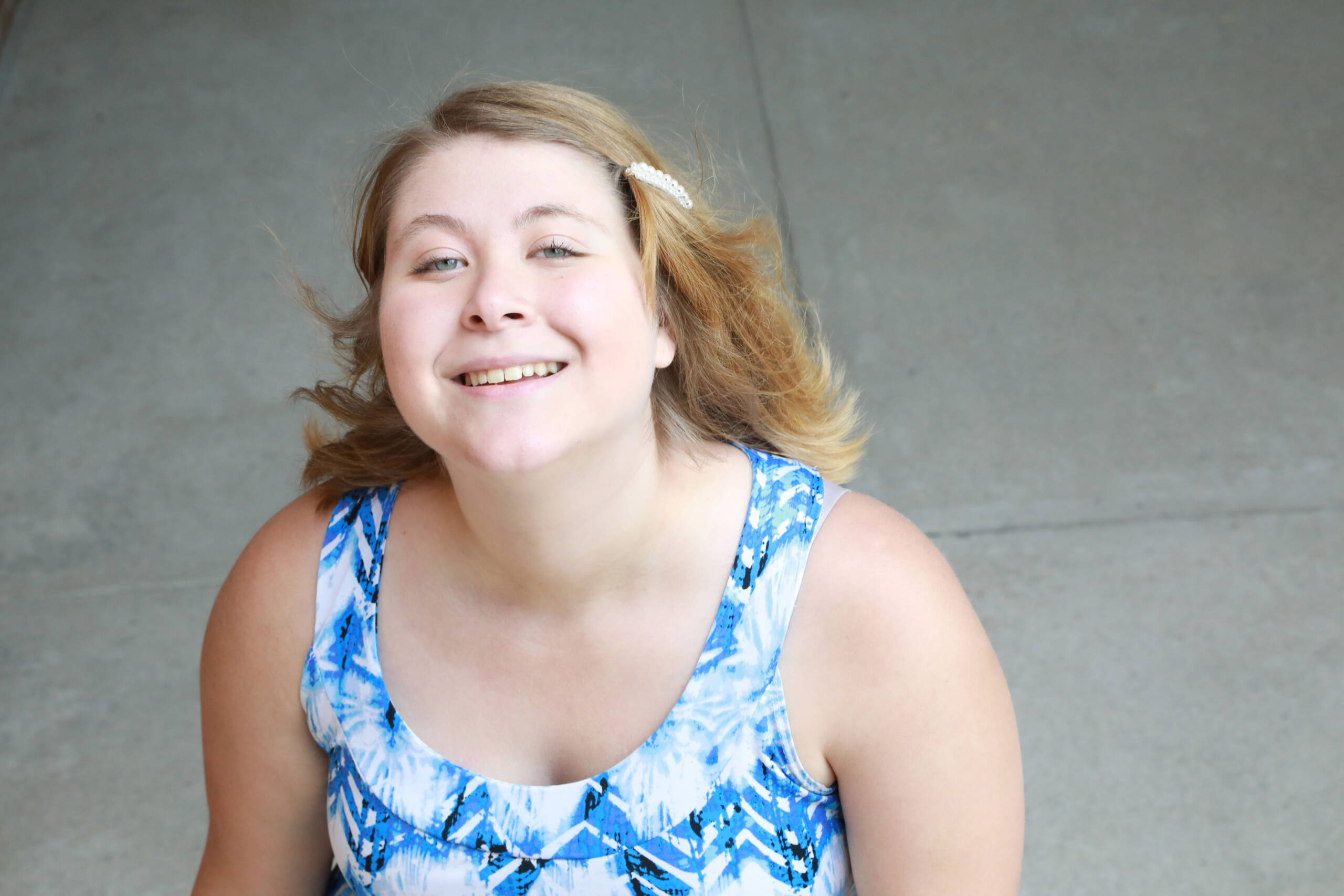 young woman with Autism wearing a blue dress looks upward to camera.