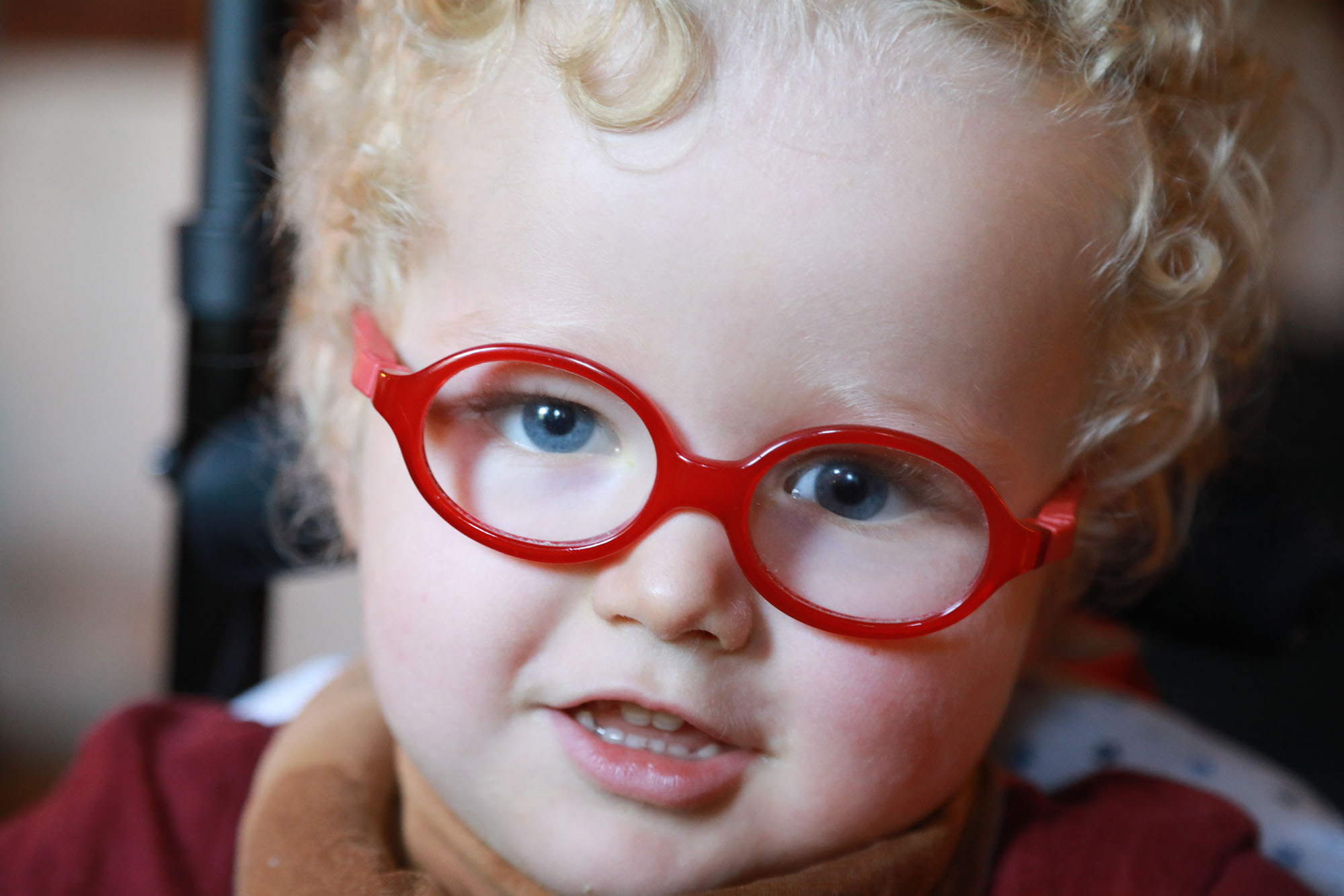 young girl with red glasses looks into the camera, closeup photo