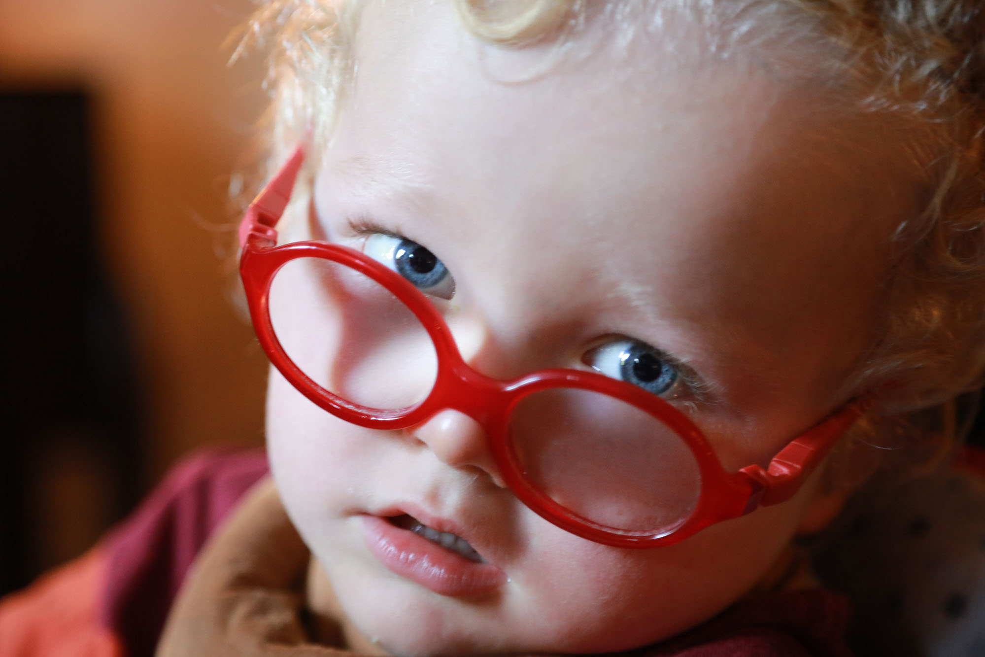 young girl with red glasses looks into the camera, closeup photo
