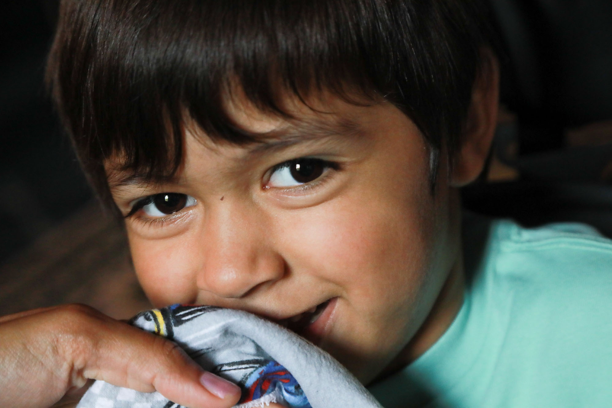 young boy with turquoise shirt smiling, closeup photo