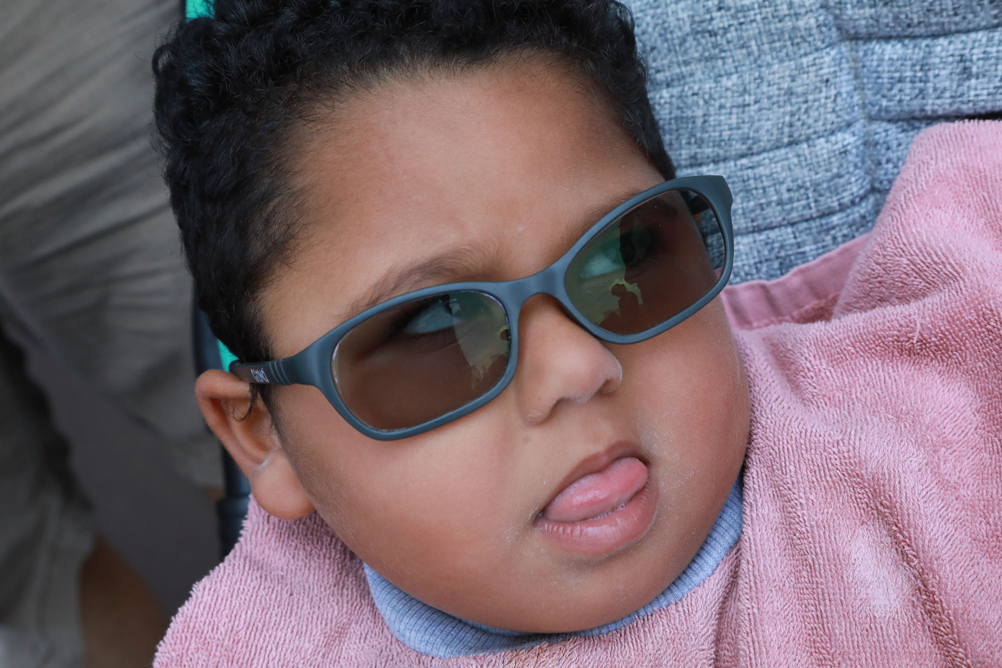 young girl with pink shirt and grey sunglasses looking to the right