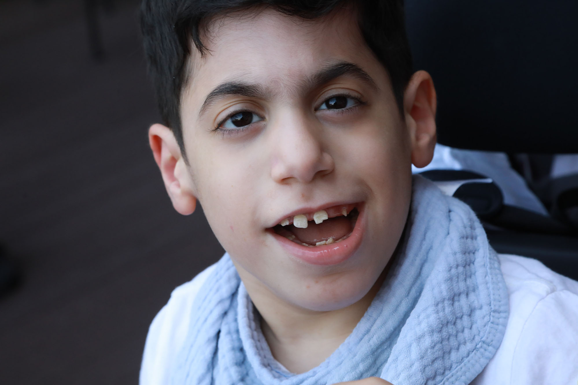 boy wearing white and smiling at the camera, closeup photo