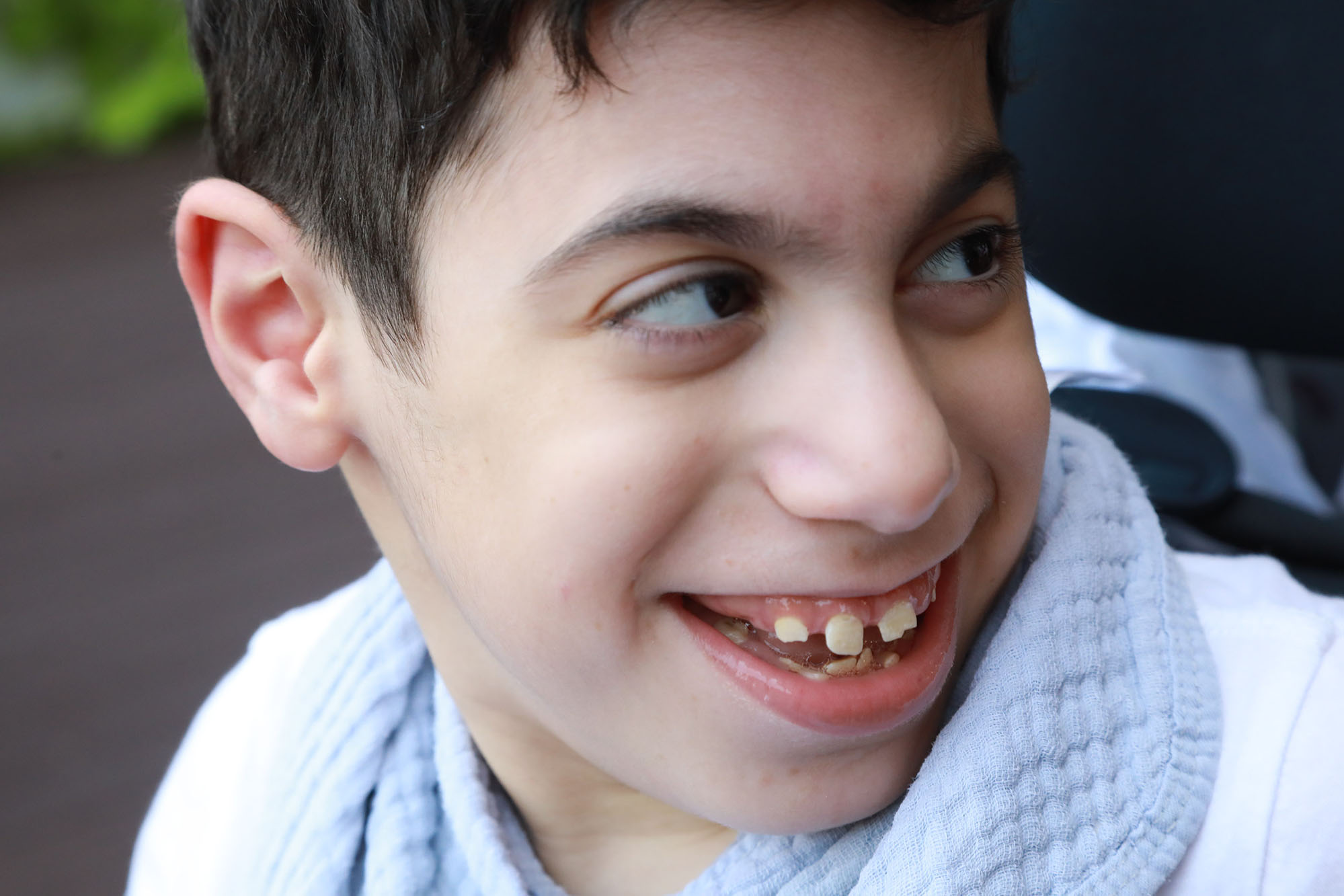 boy wearing white and smiling while looking to the right, closeup photo