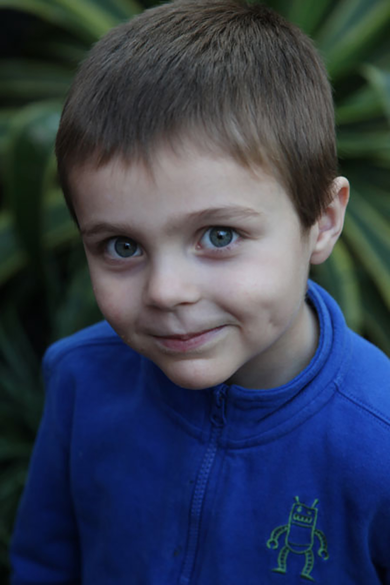 young boy with dravet syndrome wearing blue shirt smiling at camera