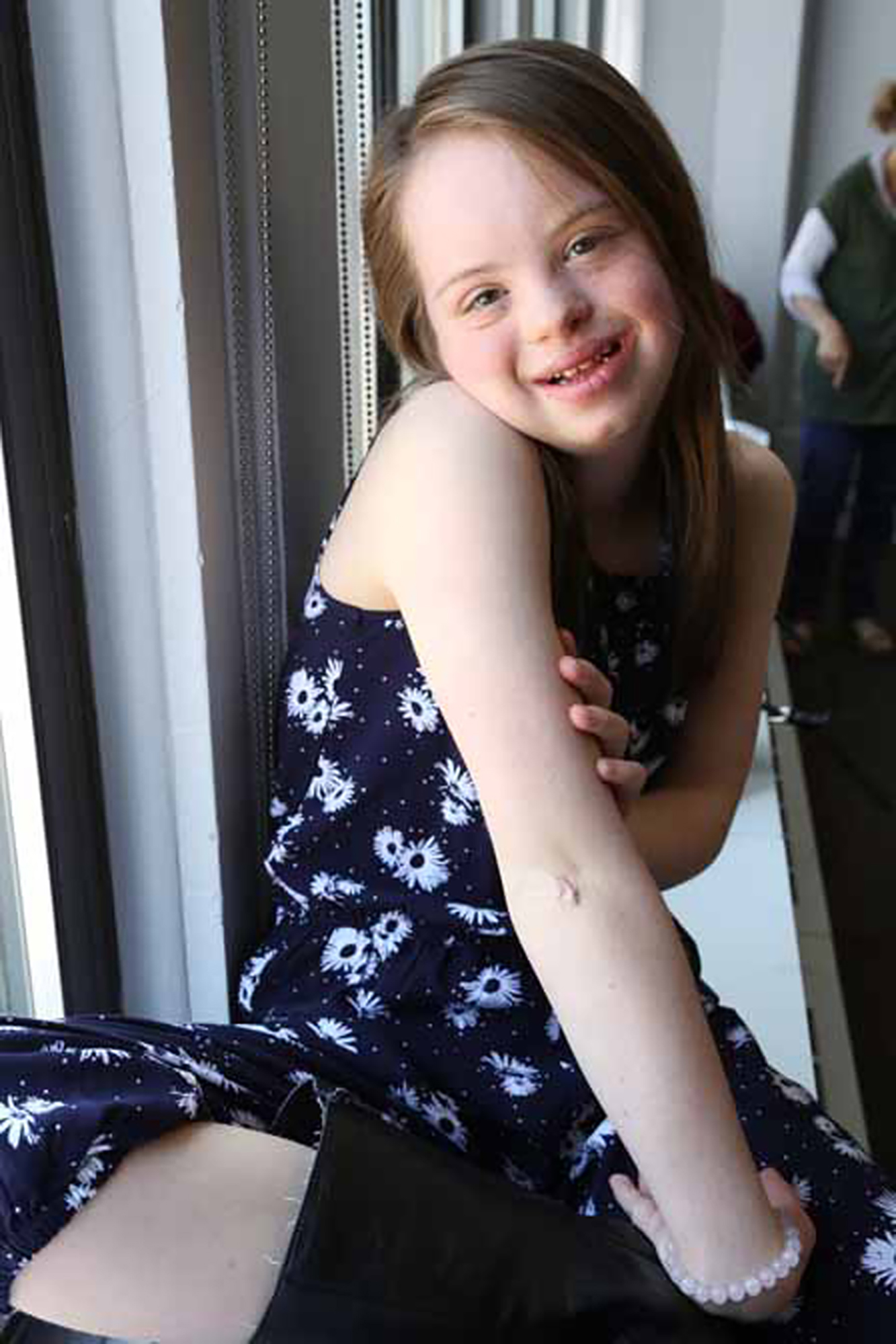young girl with down syndrome smiles at camera