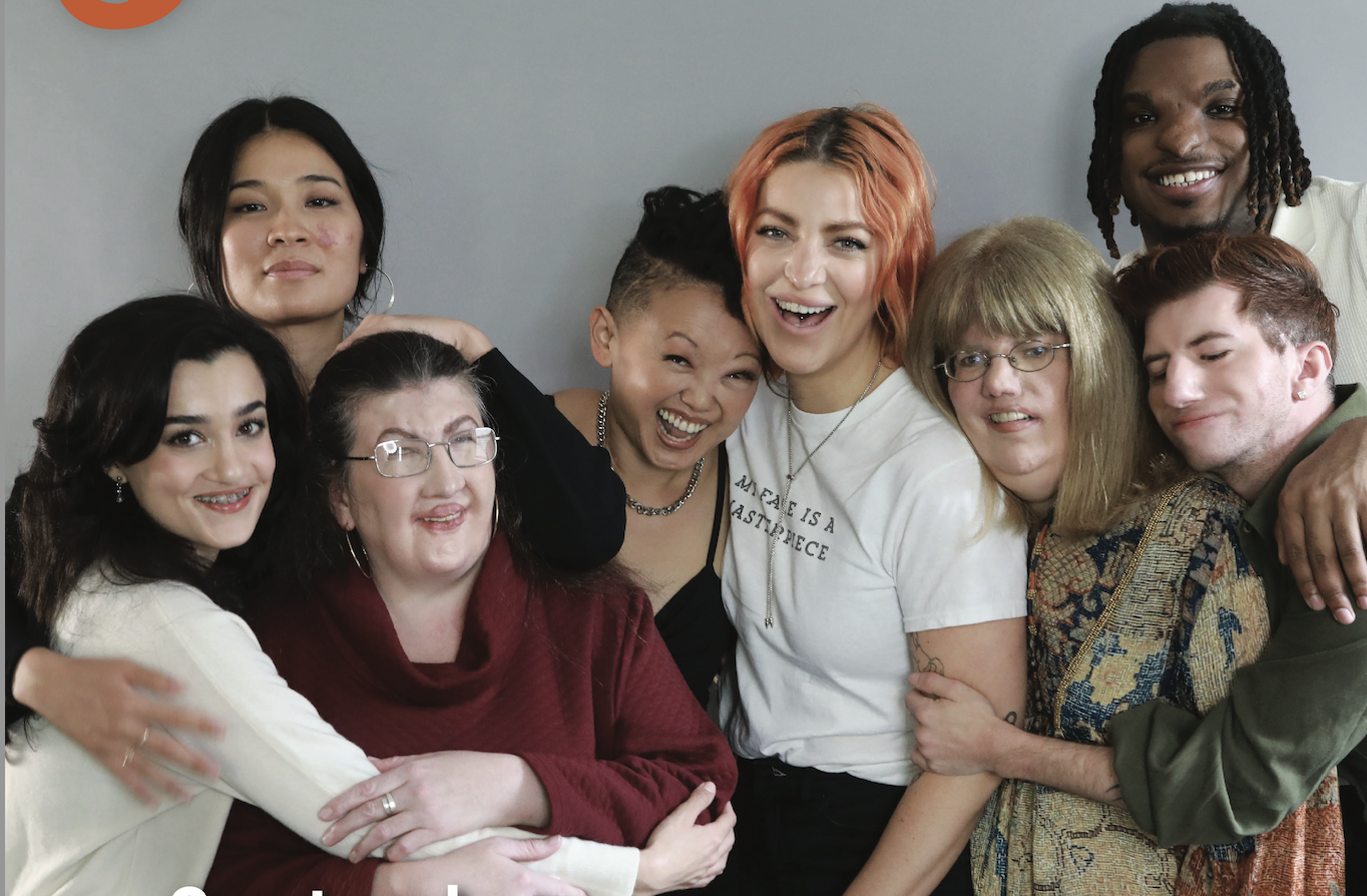 8 friends hugging against a light grey backdrop