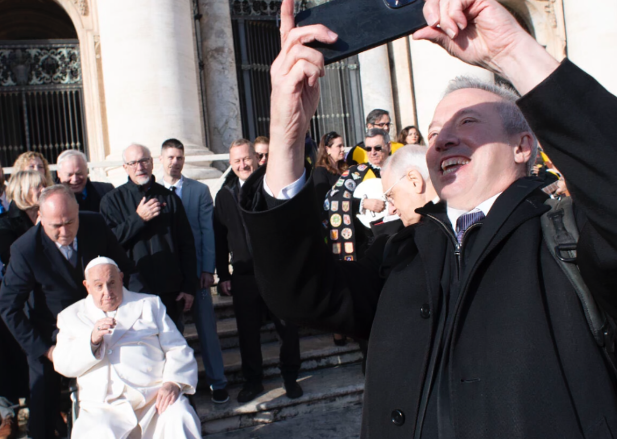 Rick making a selfie with the Pope (man in white) in the background.