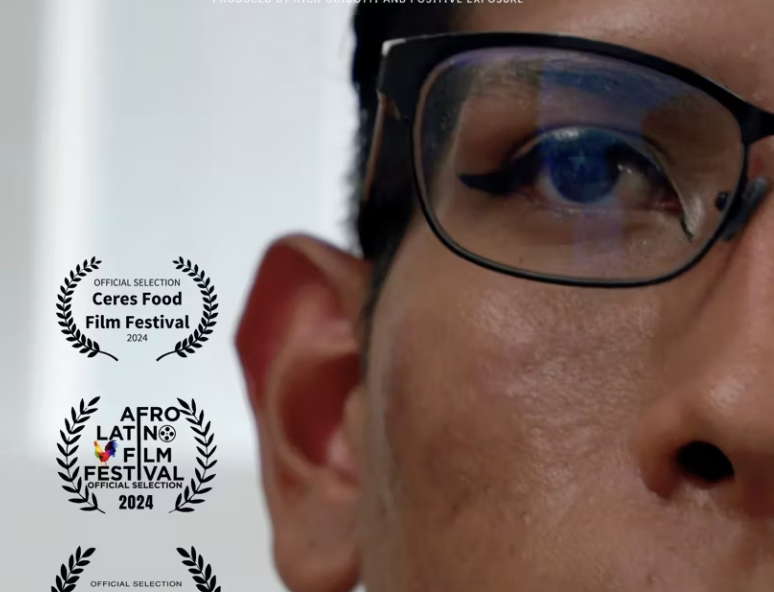 Tight shot of man with glasses. He is wearing eyeliner.