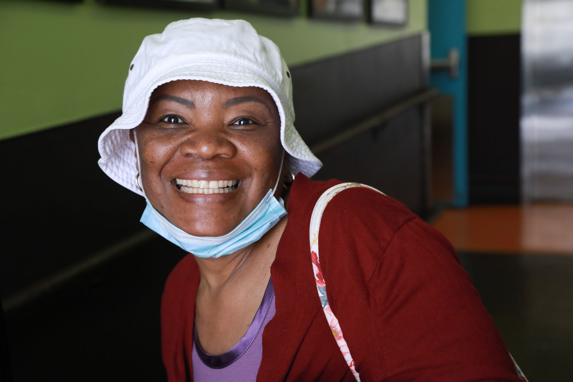 Woman in white hat wearing a red sweater and smiling into the lens.