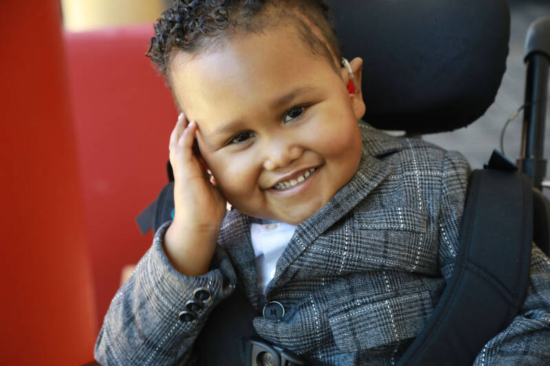 boy with curly brown hair smiling into the camera