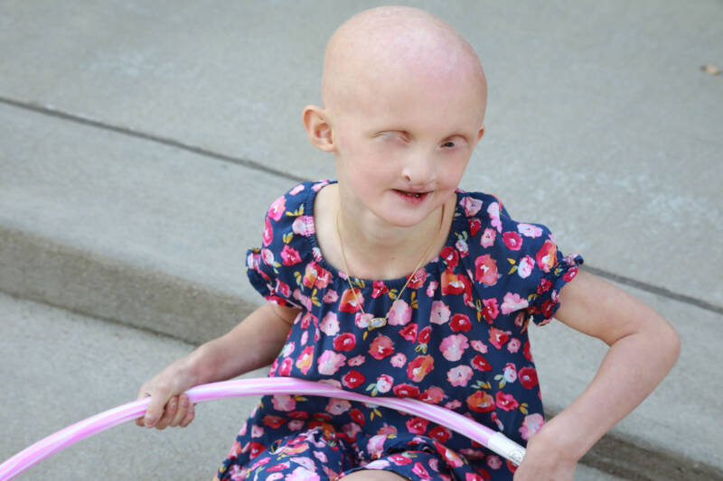 Young lady in a printed dress holding a hula hoop.