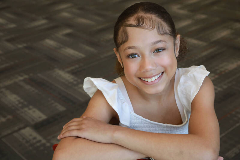 Young lady with white ruffled top smiling.