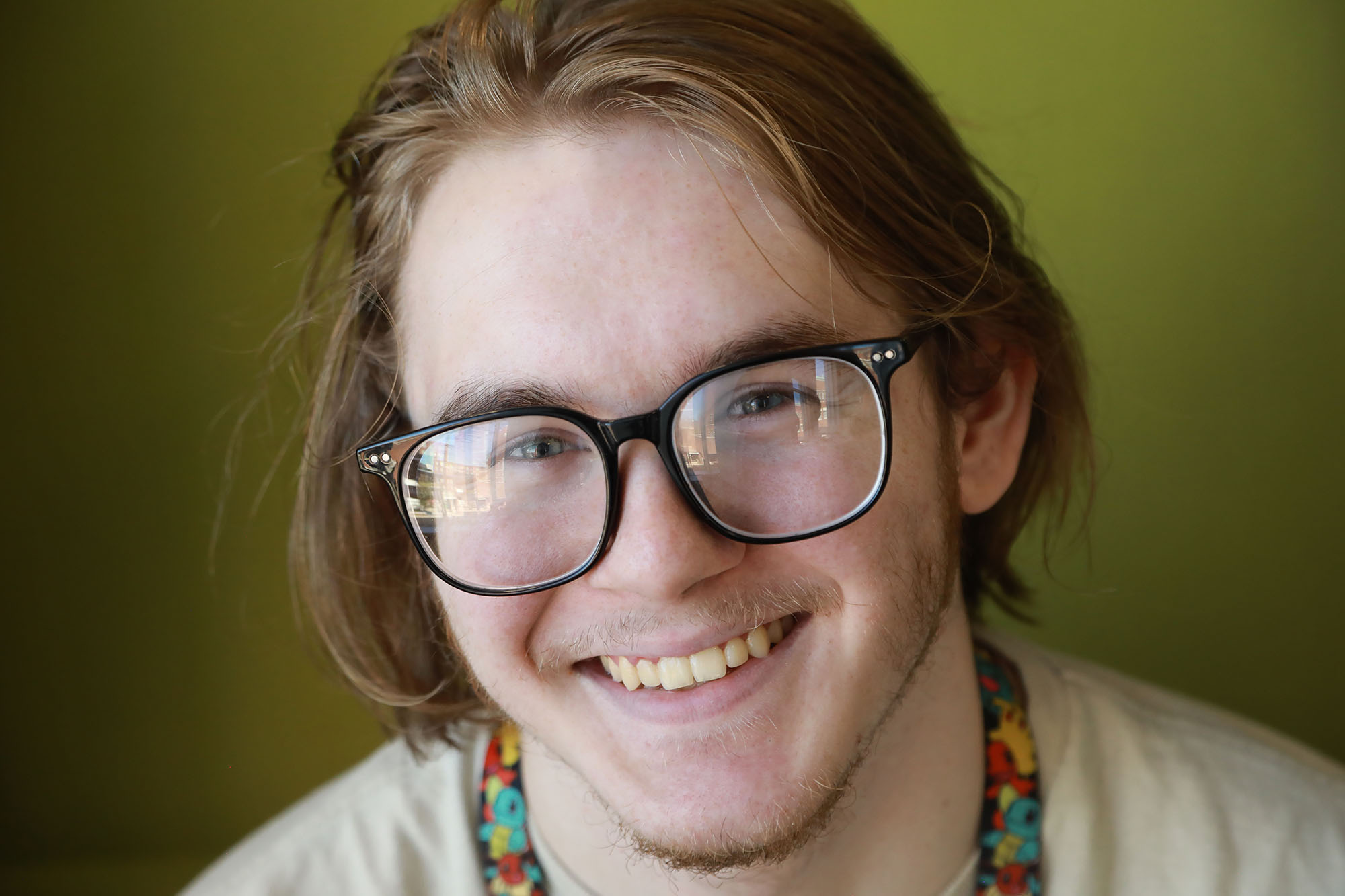 Person with long hair and glasses smiling.