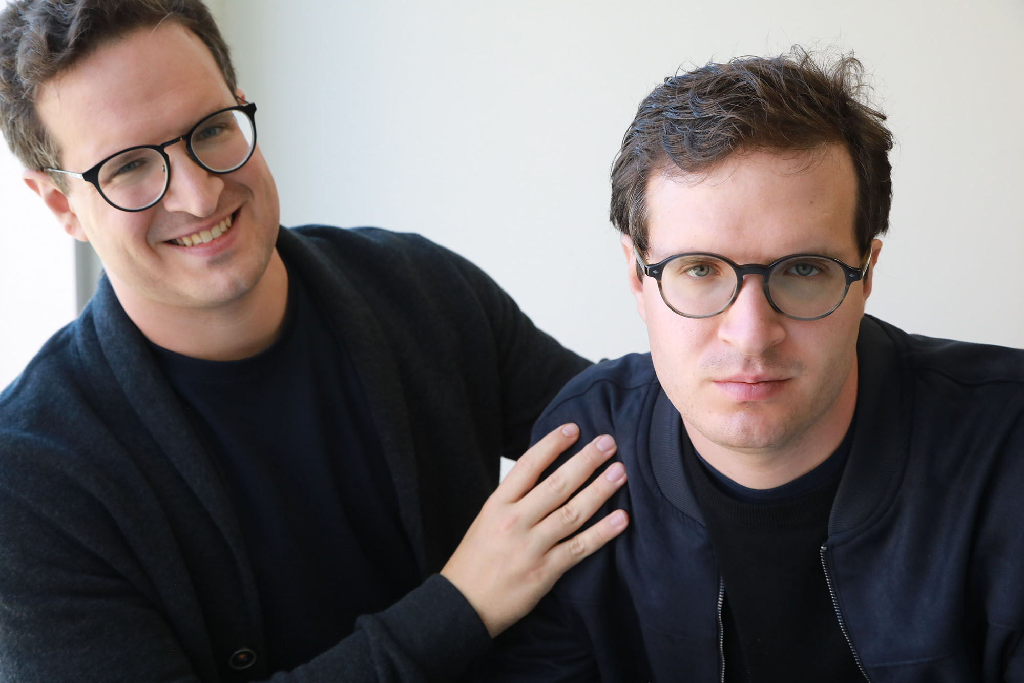 2 guys looking into the camera, one is laughing