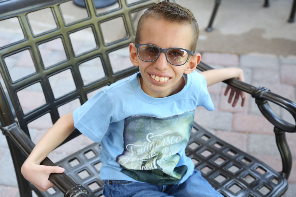young man sitting on a chair with glasses, smiling.
