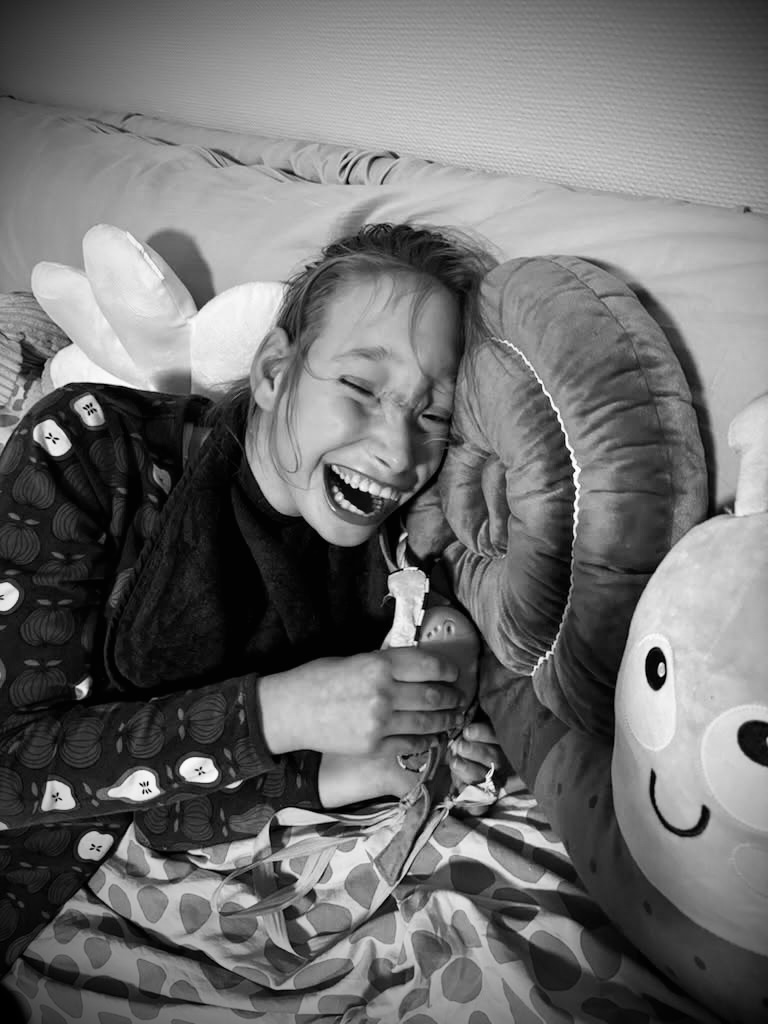 Young lady laughing against a pillow.