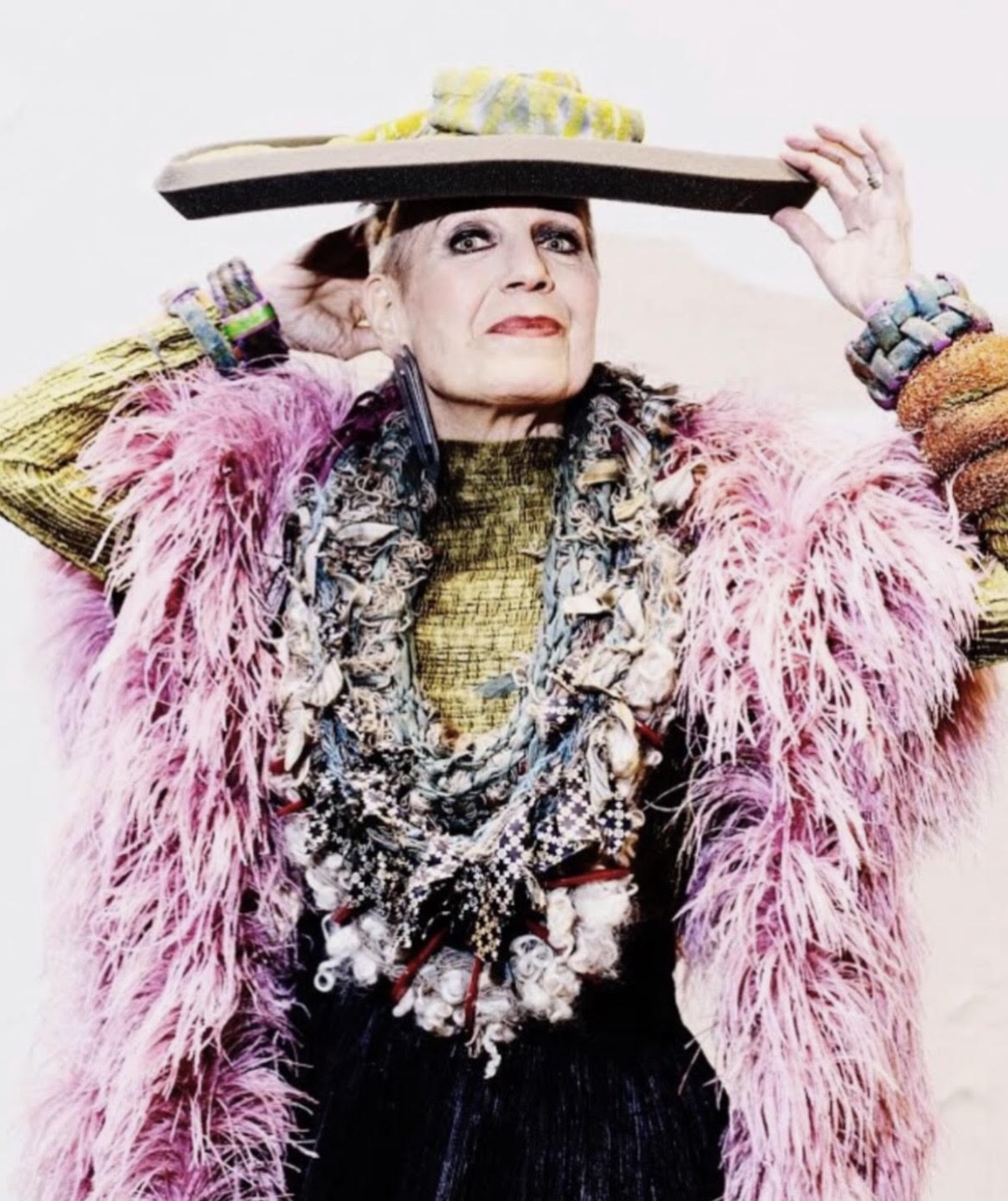 A WOMAN WITH A BIG HAT AND LOTS OF FEATHERS POSING FOR THE CAMERA