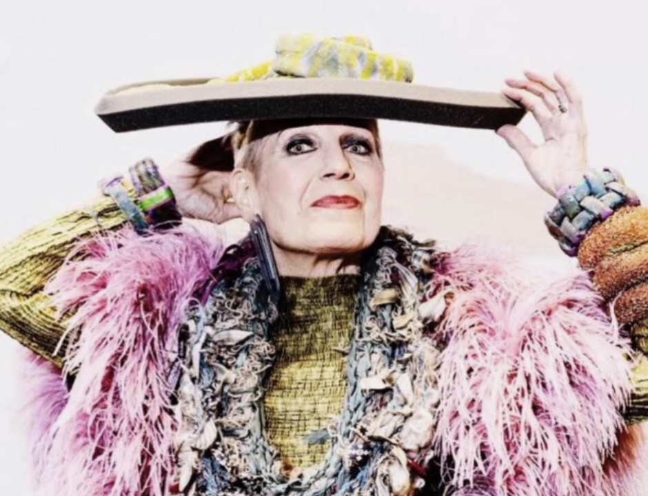 A WOMAN WITH A BIG HAT AND LOTS OF FEATHERS POSING FOR THE CAMERA