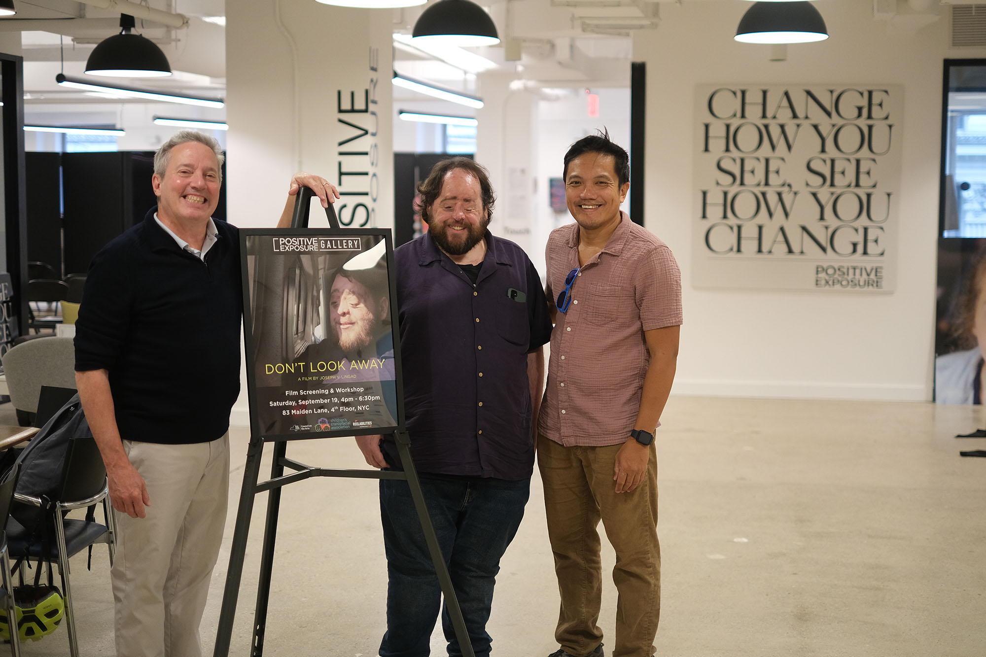 3 m3n standing in front of a movie poster at the gallery